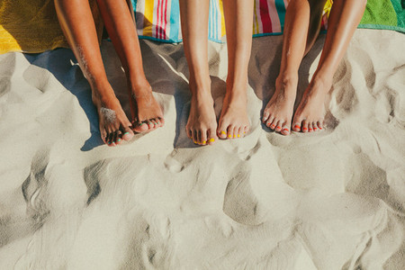 Close up of legs of three women at the beach
