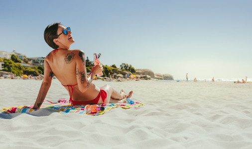Woman in swimsuit sunbathing on beach
