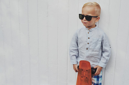 Serious trendy little boy posing with a skateboard