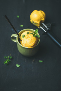 Mango sorbet ice cream scoops with fresh mint in cup