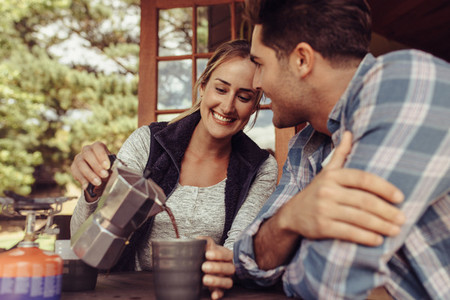 Woman serving coffee to her boyfriend in morning