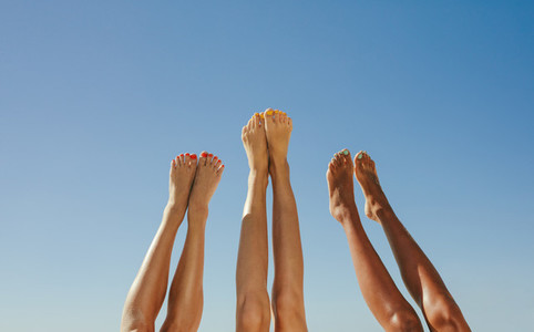 Close up of legs of three women raised up in the air