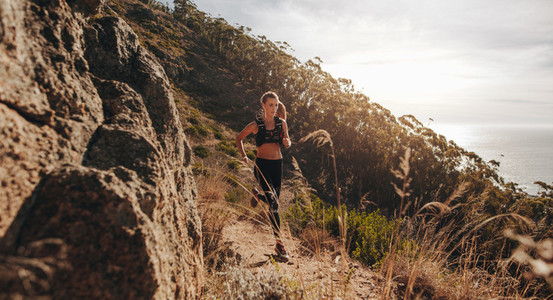 Woman running over extreme terrain on the hillside