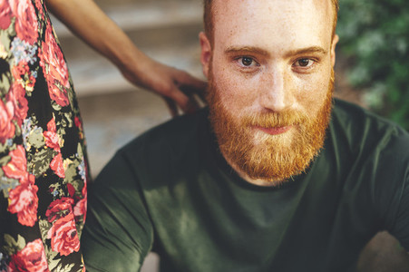 Portrait of red head bearded man with the arm of his girlfriend over the shoulder