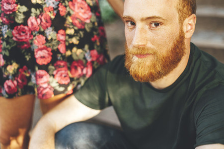 Portrait of red head bearded man with the arm of his girlfriend over the shoulder