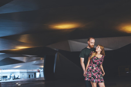 Young couple looking each other under arquitectural urban structure
