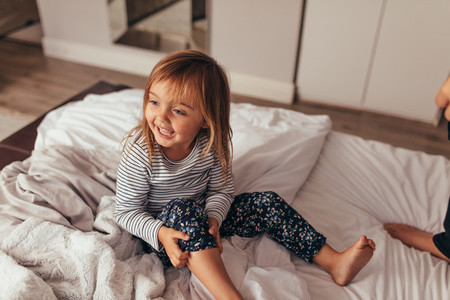 Little girl playing on bed
