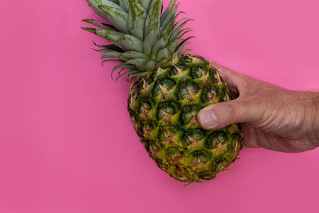 Pineapple fruit held in hand on pink background minimal summer f