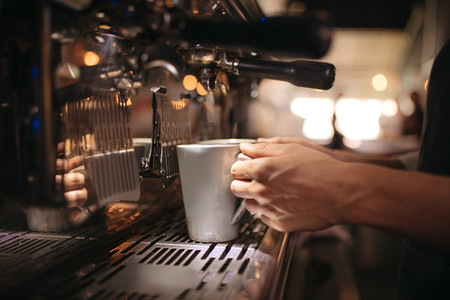 Female cafe worker preparing coffee in machine