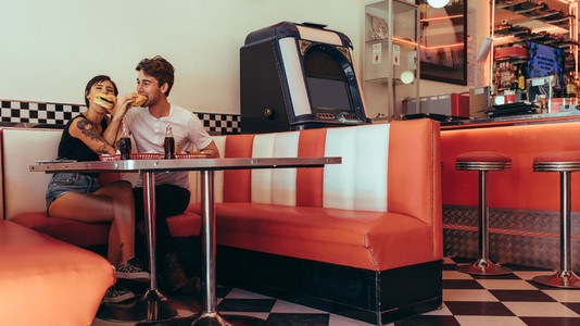 Romantic couple eating burgers at a diner