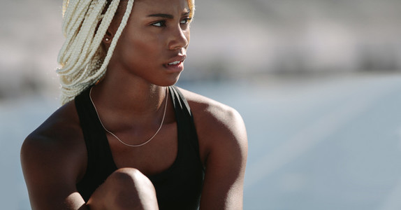 Portrait of a female athlete sitting on running track