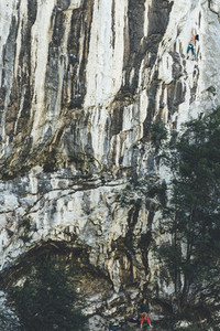 Mature strong woman climbing limestone wall with vertical lines as a cebra