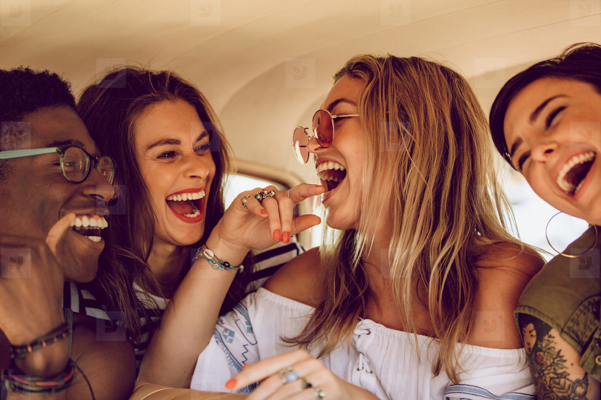  Four people are laughing and having fun together in a car.