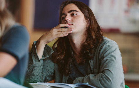 Male student listening to lecture in classroom