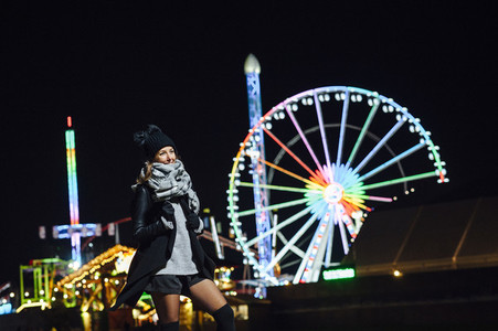 Portrait of a smiling woman  in winter at night with funfair at background