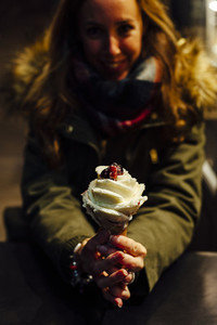 Young blonde woman eating ice cream at night with Christmas lights