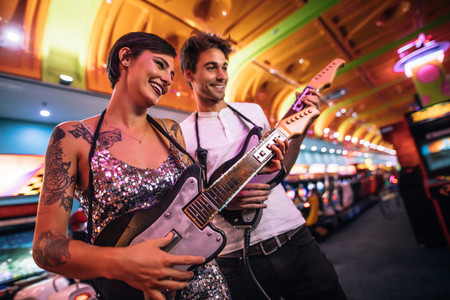 Couple playing guitar arcade game looking at the console