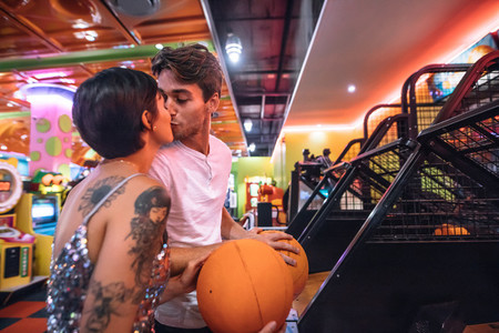 Romantic couple kissing at a gaming arcade