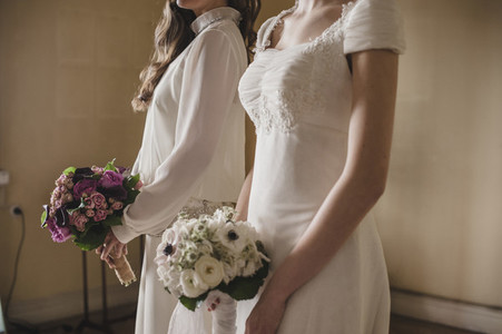 Two young brides holding her bridal bouquets