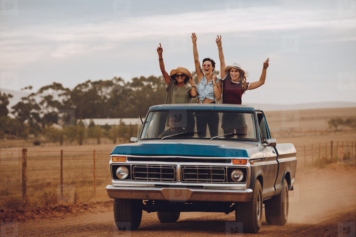 Excited friends traveling by a pickup truck