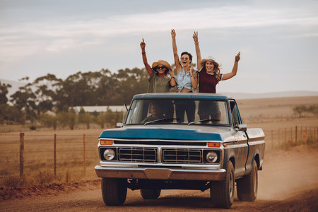 Excited friends traveling by a pickup truck