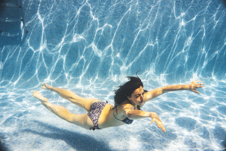 Underwater side view of a woman swimming in a pool summer time