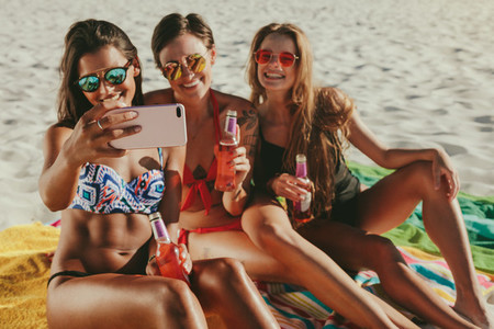 Women sitting at the beach taking a selfie