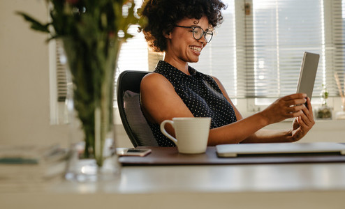 Happy woman using digital tablet in office