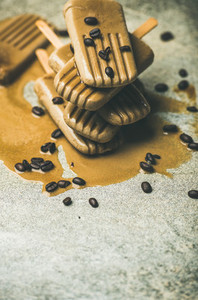 Melting coffee latte popsicles with roasted coffee beans marble background
