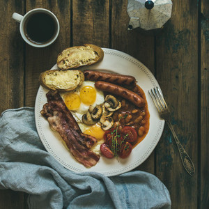 Traditional English breakfast with fried eggs  sausages  mushrooms  bacon  coffee