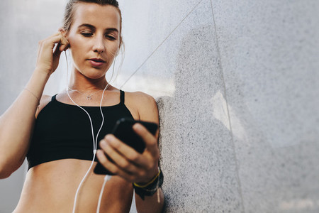 Women in fitness wear listening to music using earphones