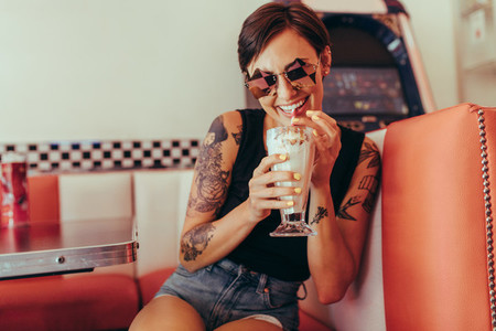 Smiling woman at a diner drinking milkshake