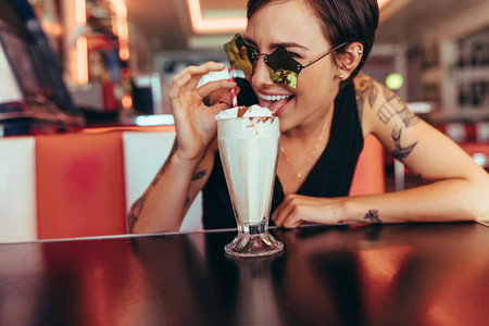 Woman enjoying her ice cream milkshake sitting at a restaurant