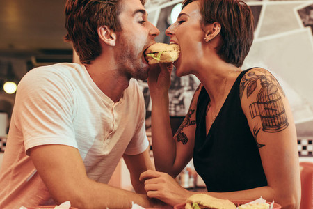 Happy couple sharing a burger at a restaurant