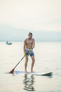 Young european man tourist practicing paddle boarding