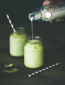 Refreshing iced coconut matcha latte and hand pouring milk