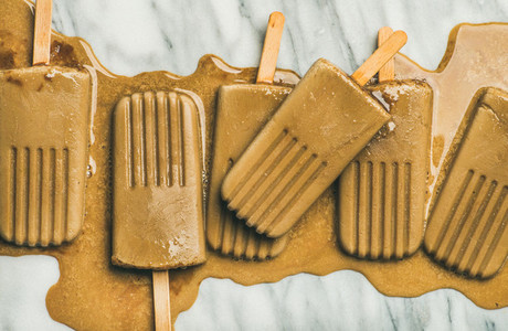 Flatlay of melting coffee latte popsicles on grey background