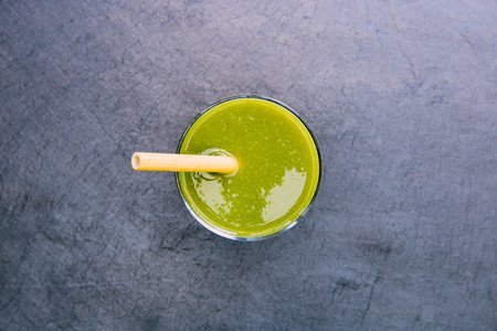 Green smoothie drink with straw dark background