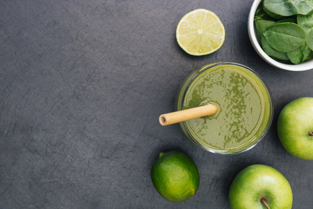 Green smoothie drink with straw on dark background copy space