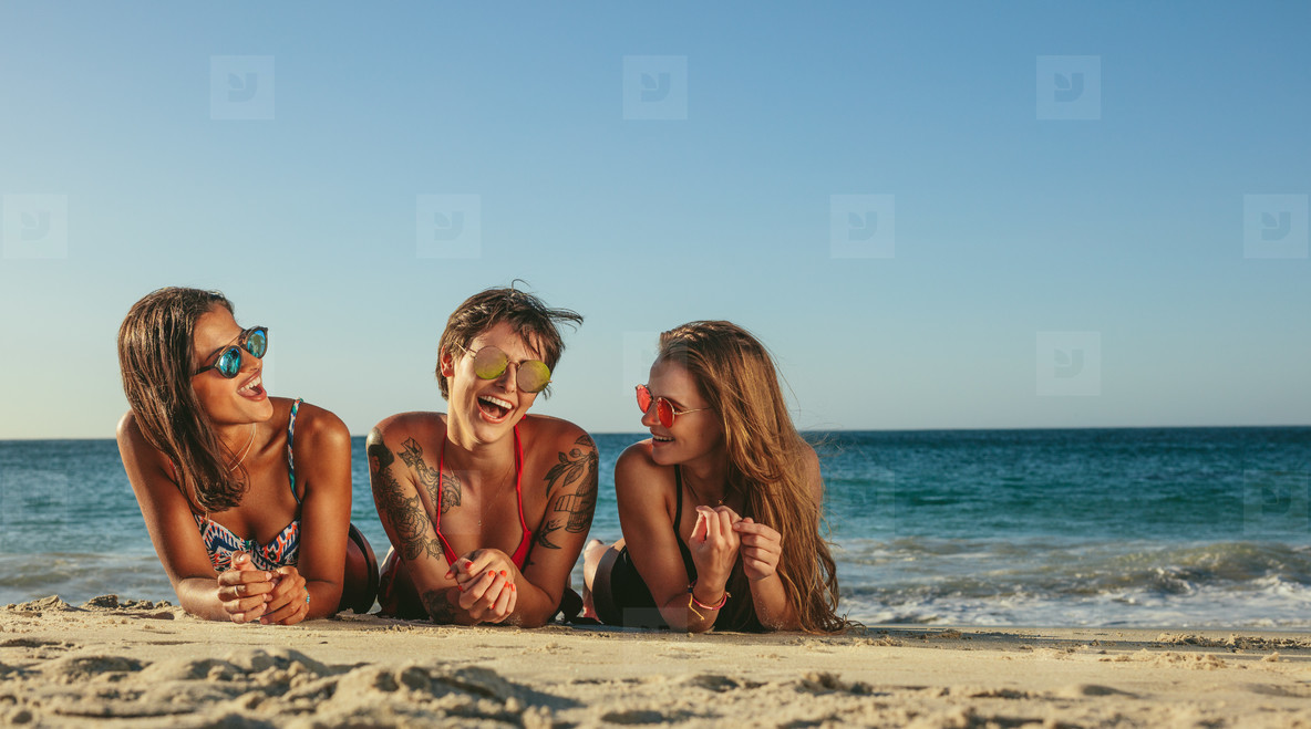 Woman friends relaxing at the beach and talking