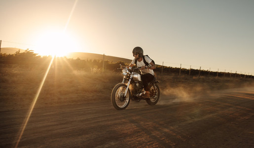 Biker driving a vintage motorcycle on dirt road