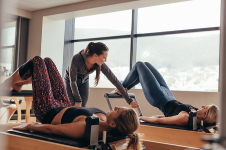 Pilates trainer instructing women at the gym