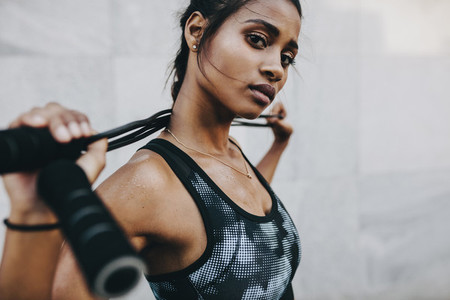Portrait of a fitness woman standing with a skipping rope on her