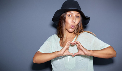 Playful romantic young woman making a heart sign