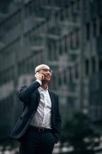 Business executive talking over mobile phone standing outdoors