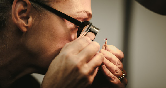 Senior woman goldsmith checking quality of diamond
