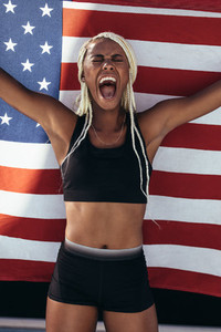 Female athlete celebrating victory holding american flag