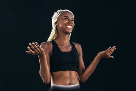 Smiling female athlete standing against black background