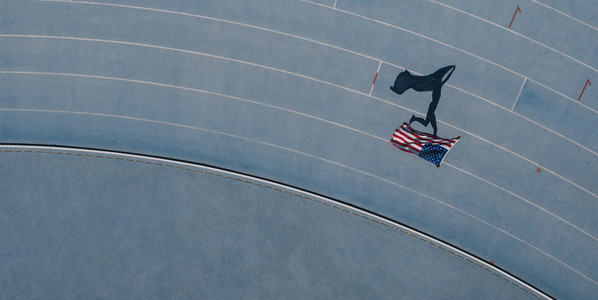 Athlete running on the track holding flag celebrating win