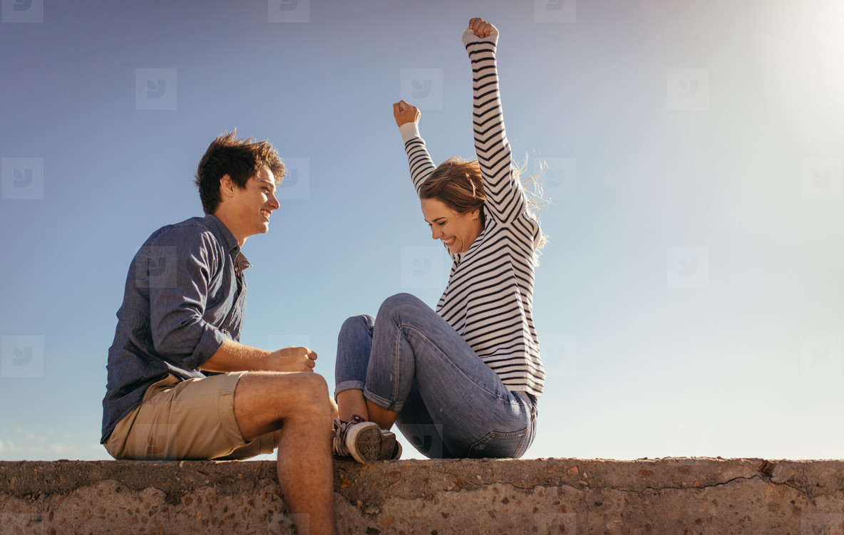 Happy couple having fun sitting on a sea wall